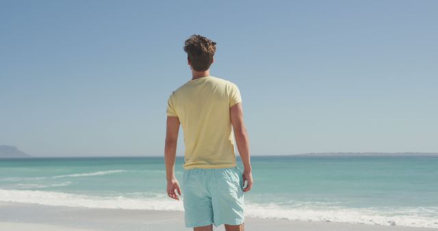 Man in Yellow T-Shirt and Blue Shorts Standing on Beach - Download Free Stock Images Pikwizard.com