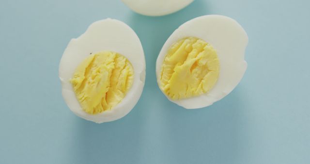 Image of overhead view of three egg halves on blue background. fusion food, eggs and easter concept.