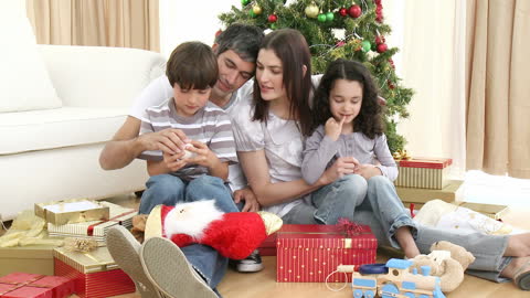 Happy Family Opening Christmas Gifts by Festive Tree