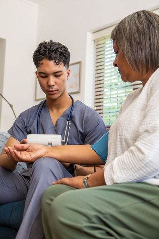 Home healthcare worker checking senior patient's blood pressure