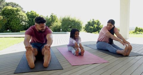 Diverse Family Practicing Yoga Stretches on Outdoor Deck