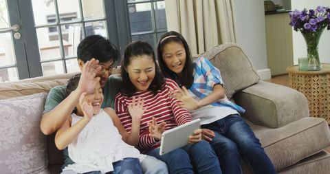 Asian Family Bonding with Tablet at Home While Laughing