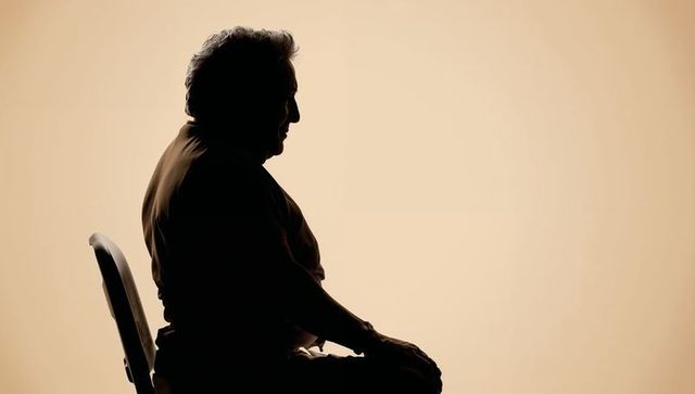 Silhouette senior man sitting on chair wearing short-sleeve shirt minimalist beige profile