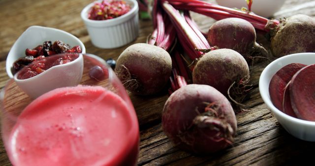 Fresh beetroots are displayed on a wooden surface alongside a glass of beetroot juice and small bowls containing beetroot salad and seeds, with copy space. Beetroots are often used in healthy diets due to their nutritional benefits and vibrant color.