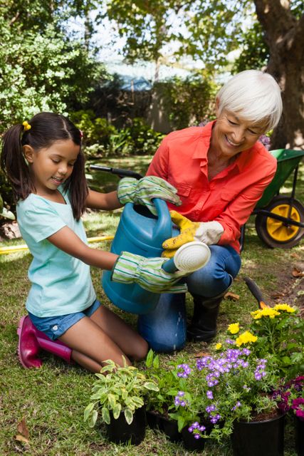 Grandmother and granddaughter enjoying time together in the garden, watering plants and nurturing flowers. Ideal for use in family-oriented content, gardening blogs, outdoor activity promotions, and advertisements focusing on multigenerational bonding and nature.