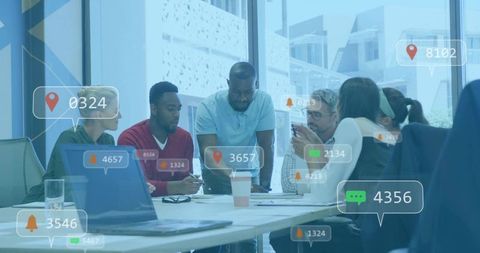 Diverse team collaborating around meeting table with digital notifications and analytics