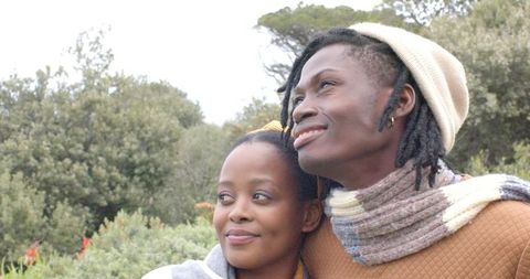 Young African American Couple Embracing Outdoors Smiling and Looking Up in Cozy Fall Clothing