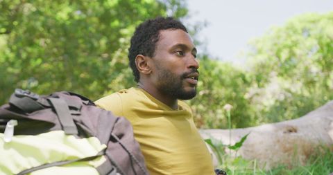 Young Man Relaxing Outdoors with Backpack in Lush Park