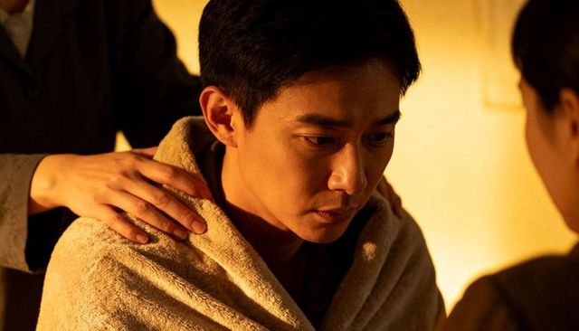 Sitting pensive man wearing towel receiving comforting hand under warm lamp glow