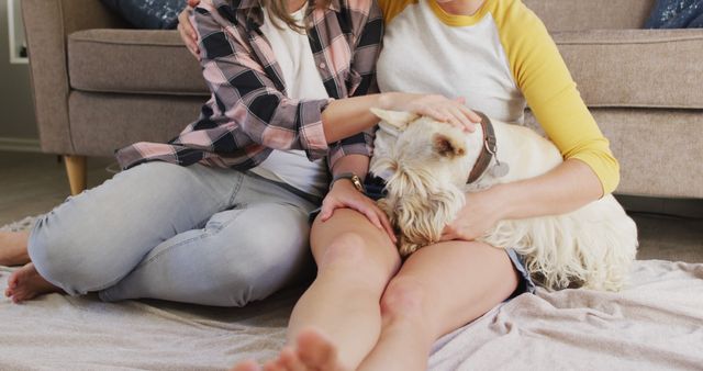 Caucasian lesbian couple smiling while playing with their dog at home. lgbt relationship and lifestyle concept