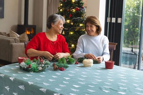 Friends crafting festive wreaths in warm holiday living room