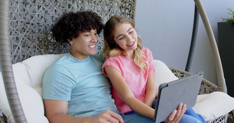 Couple Enjoying Tablet Conversation on Patio Lounge Chair