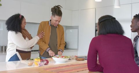 Friends Chopping Vegetables and Laughing at Kitchen Island While Preparing Fresh Salad