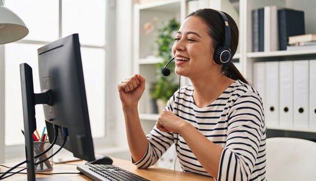 Cheerful customer support agent celebrating success during remote call in bright home office