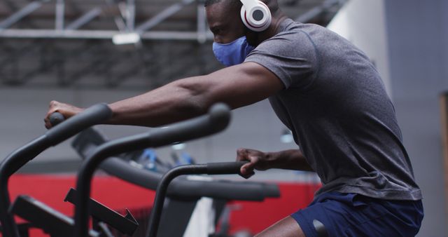 Focused Athlete On Exercise Bike Wearing Face Mask And Headphones - Download Free Stock Images Pikwizard.com