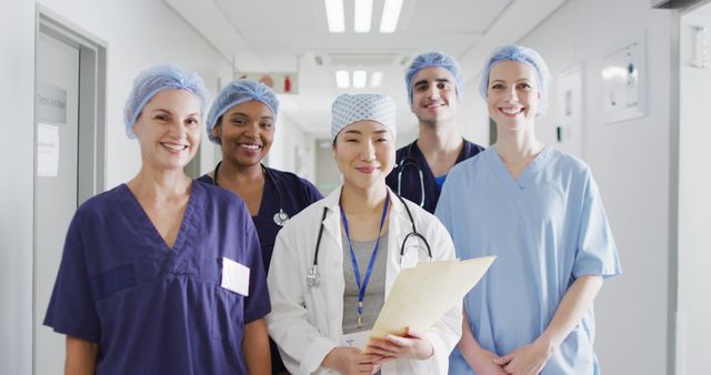 Image of diverse group of happy medical workers in surgical caps smiling in hospital corridor. Hospital, medical and healthcare services.