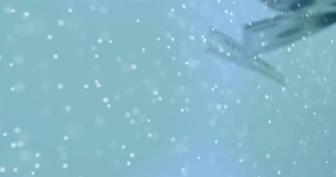 Teal bokeh snowfall with metallic wing detail abstract motion background for advertising