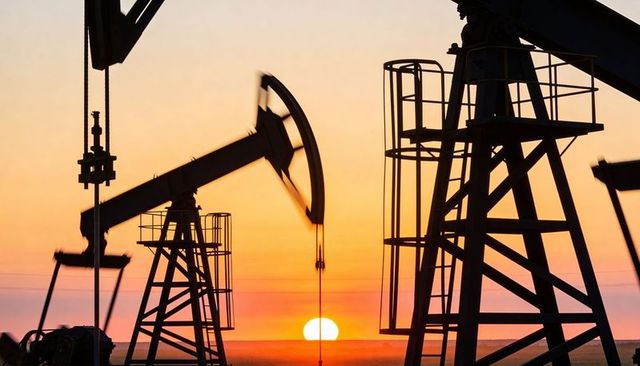 Sunset pumping oil pumpjacks silhouettes on flat plain with moving nodding donkeys