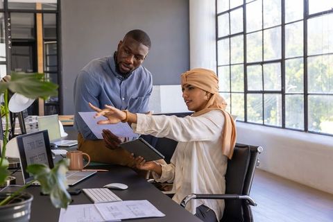 Diverse Coworkers Analyzing Blueprints in Modern Office Setting