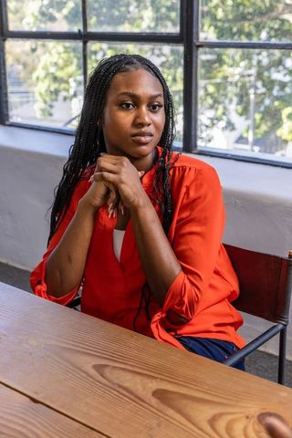 Professional african american woman in elegant red blouse seated by window