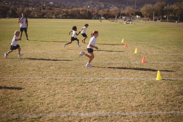 Schoolgirls participating in a running competition in a park, with cones marking the course. Ideal for illustrating outdoor sports activities, children's fitness, teamwork, and physical education. Suitable for use in educational materials, sports event promotions, and health and wellness campaigns.