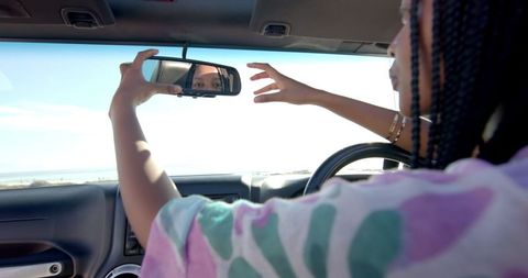 African American Woman Adjusting Rearview Mirror during Road Trip - Download Free Stock Images Pikwizard.com
