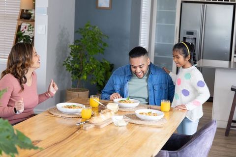 Asian family enjoying sunny breakfast together at modern kitchen table