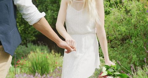 Romantic Bride and Groom Walking Hand in Hand Through Sunny Garden