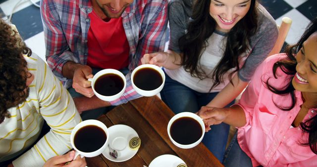 Group of diverse friends enjoying coffee together at a wooden table, creating a cheerful and relaxed atmosphere. Ideal for advertising social gatherings, coffee shops, friendship, and leisure activities.