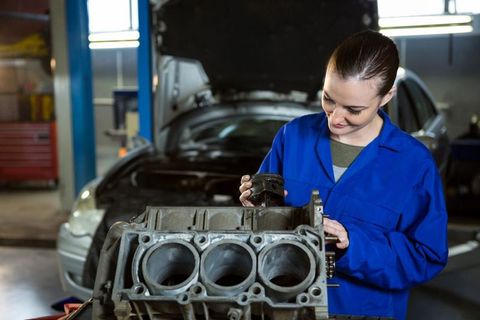 Female mechanic inspecting engine piston in workshop