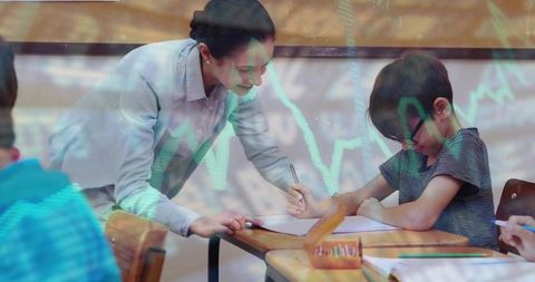 Female teacher leaning over student helping with writing at desk glasses pencils green overlay