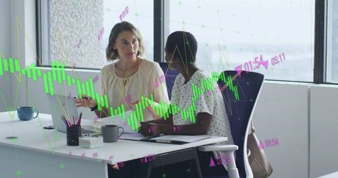 Businesswomen Discussing Financial Strategy with Digital Graphs