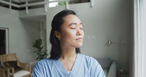 Asian Nurse Relaxing in Sunlit Hospital Room