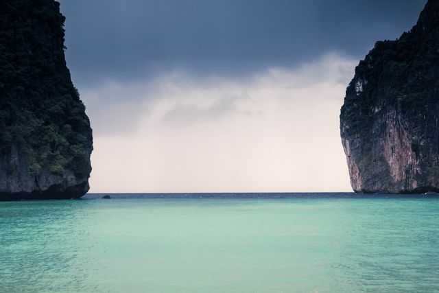 This image shows a calm turquoise sea nestled between dramatic cliffs under an overcast sky. Ideal for travel brochures, nature blogs, conservation campaigns, and serene landscape collections. Picture evokes a sense of tranquility and natural beauty.