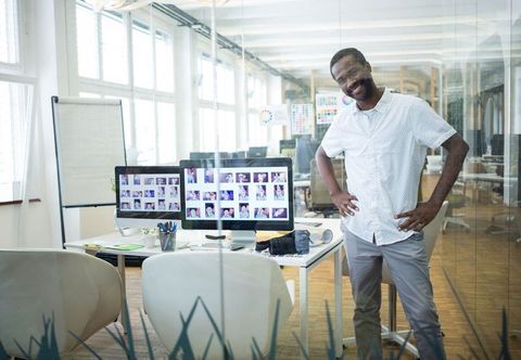 Confident professional in modern office with dual monitors and camera