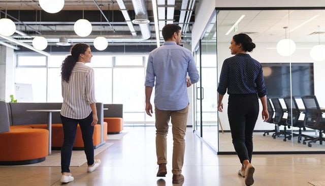 Young professionals walking through modern open-plan office corridor collaborating