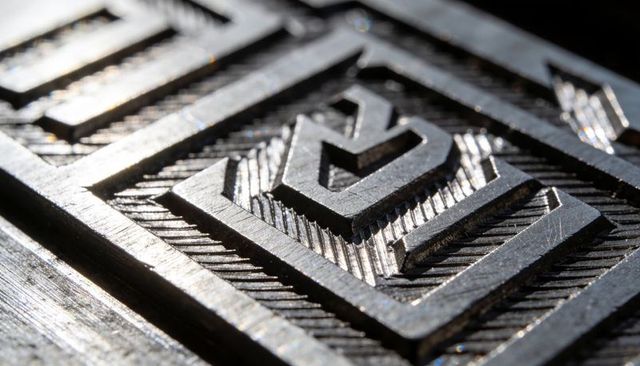 Machined steel relief block with chevron engraving macro texture and geometric detail