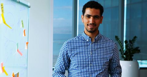 Middle eastern businessman standing in modern office with whiteboard