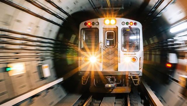 Subway train rushing through metro tunnel with headlights blurring motion and speed