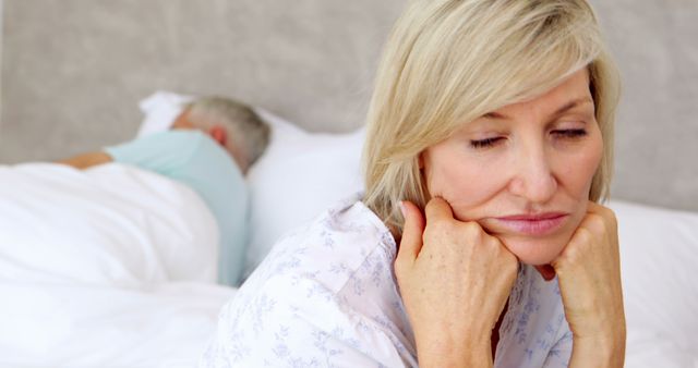 Middle-aged woman feeling sad while partner sleeps in bed - Download Free Stock Images Pikwizard.com