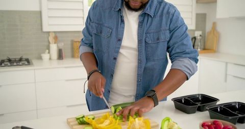 African american man chopping bell peppers at kitchen island for healthy meal prep