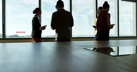 Professionals meeting in office with digital devices and city view
