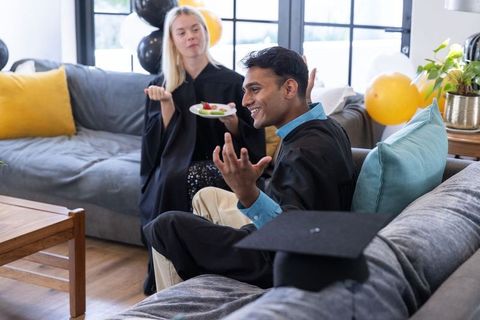 Diverse Graduates Celebrating at Home with Snacks and Decorations