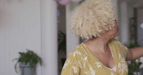 Joyful Woman Dancing at Home in Vibrant Yellow Dress
