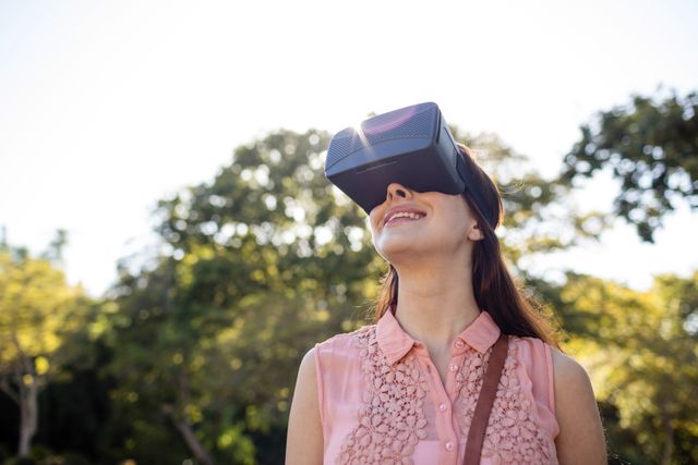Smiling woman using a VR headset in the park on a sunny day