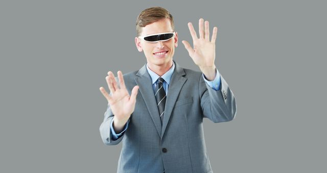 Professional businessman wearing virtual reality glasses interacting with an unseen interface. Ideal for use in articles, blogs, and marketing materials relating to technology, innovation in business, and future trends in the workplace.