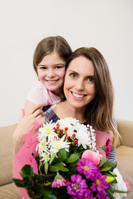 Mother receiving flower bouquet from her daughter in living room at home
