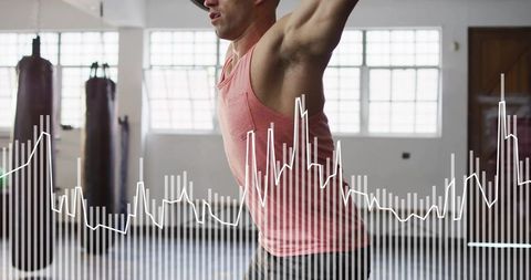Athlete raising overhead in boxing gym with fitness data waveform overlay