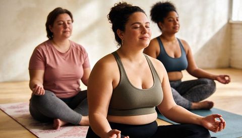 Women practicing mindful meditation in inclusive yoga class for body positive wellness
