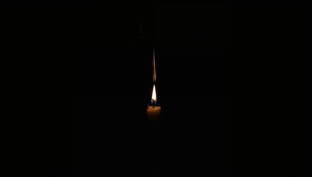 Solitary Candle Flame Emitting Warm Glow in Dark Atmosphere
